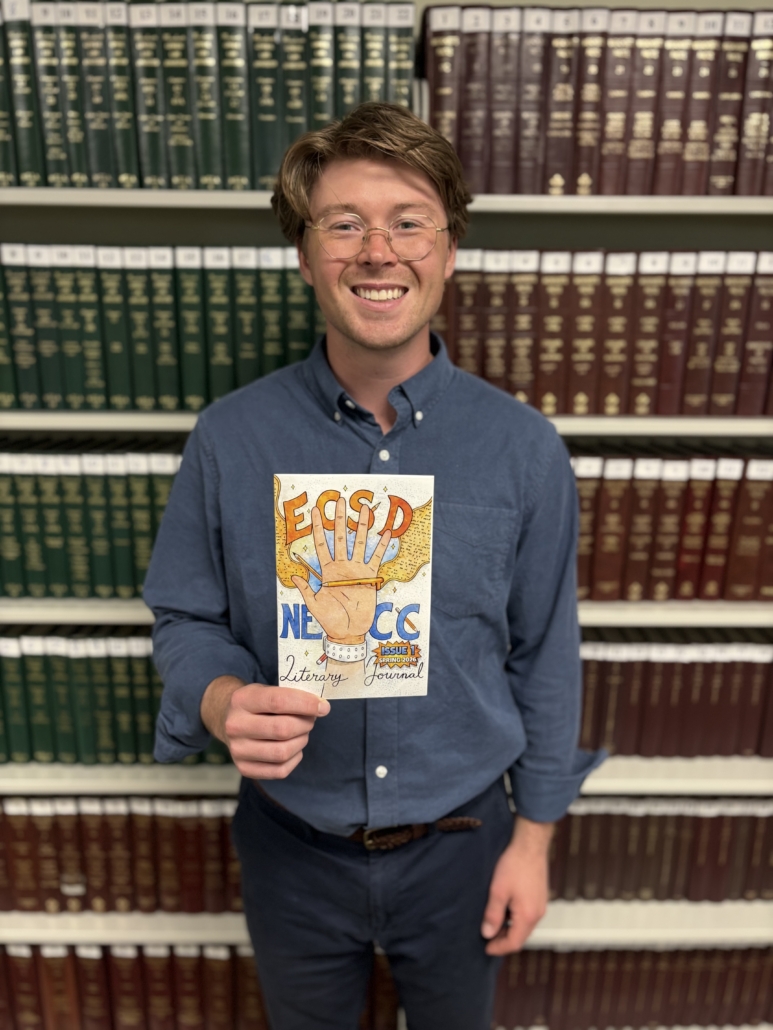 NECC Learning Specialist Alexander Hill poses with copy of literary journal