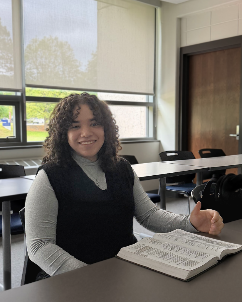 student Engely Geraldino sits at a desk in a classroom