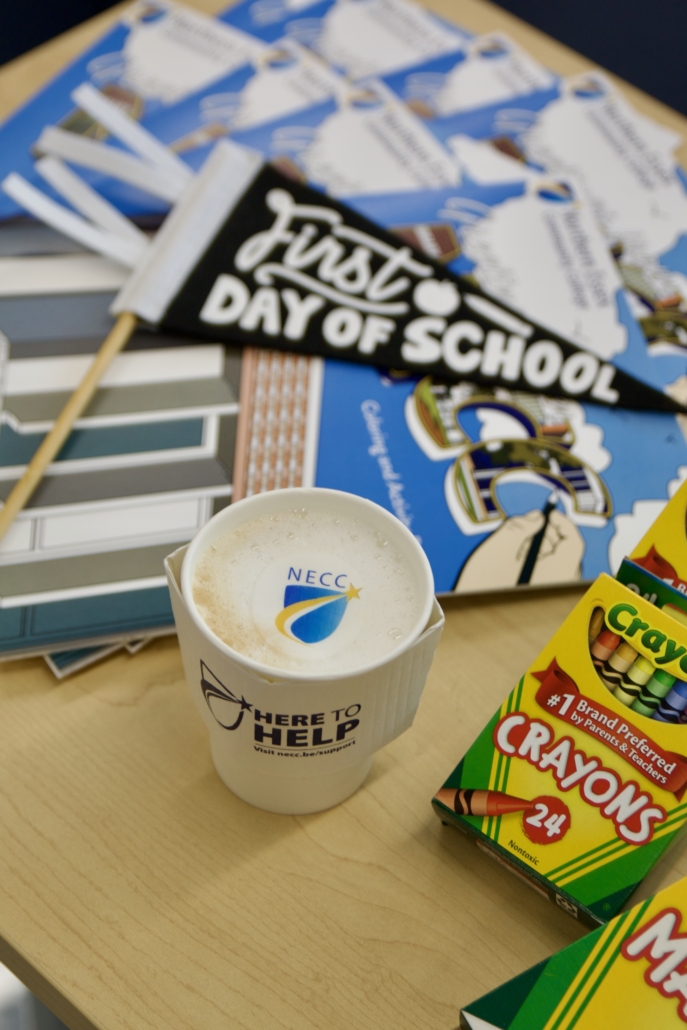 coffee cup with NECC Logo sits next to pennant and NECC flag