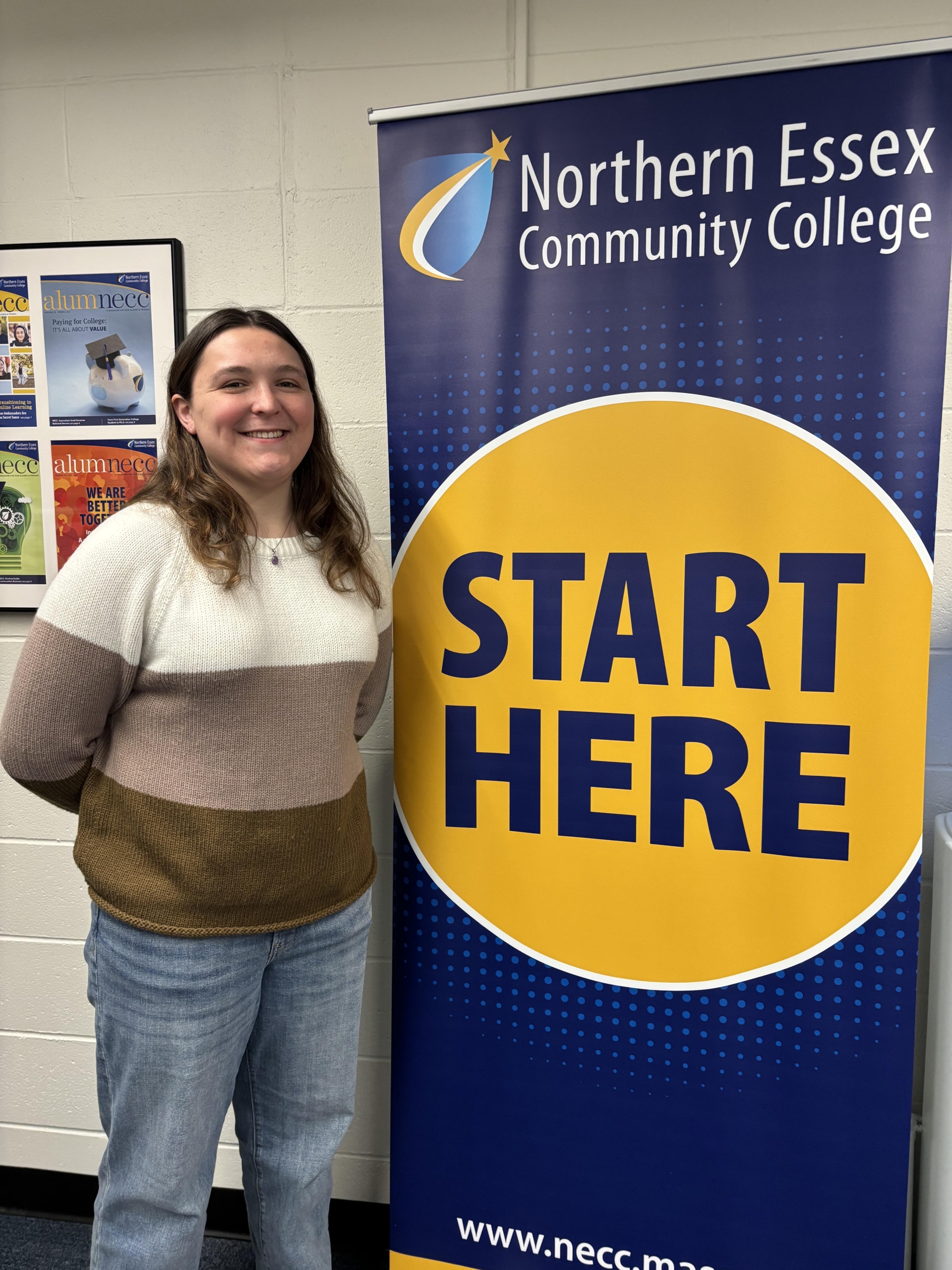 Emma posing in front of banner that says "start here"