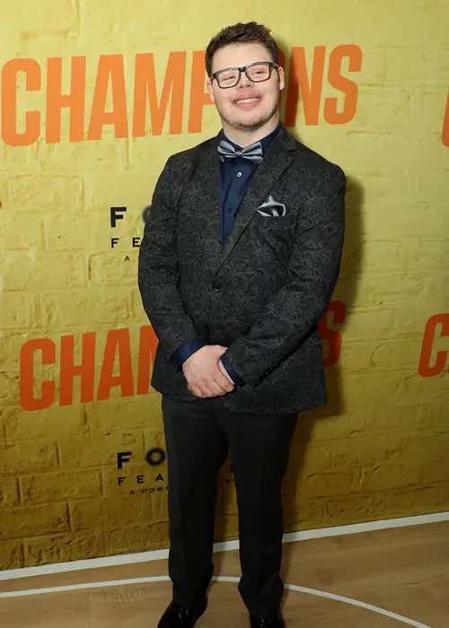 James poses in front of backdrop with the movie title "Champions" written on it