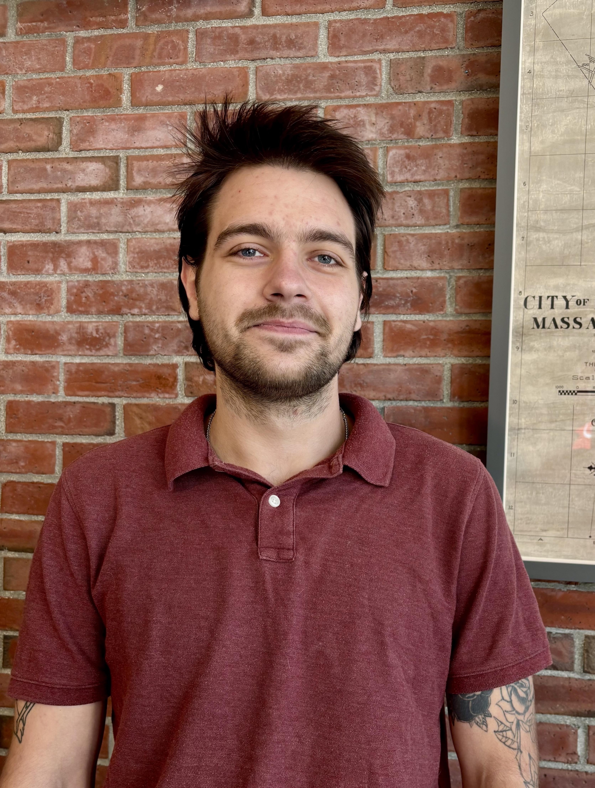 nick smiles at the camera in front of brick background