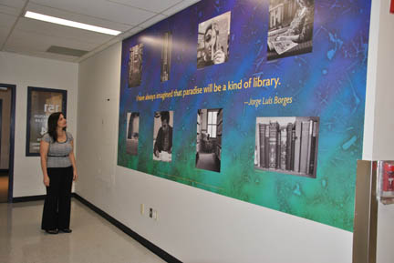 NECC Librarian Jennifer Fielding gazes up at the newest mural financed by the NECC Fund, titled "The Library".