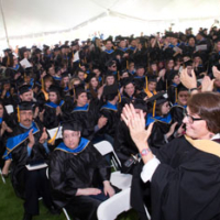 wide shot of room full of graduates in caps and gowns