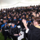 wide shot of room full of graduates in caps and gowns