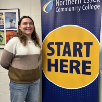 Emma posing in front of banner that says "start here"
