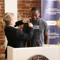 woman gives pin to young man standing behind a podium