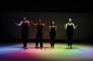 NECC theater performers performing under rainbow lights on stage