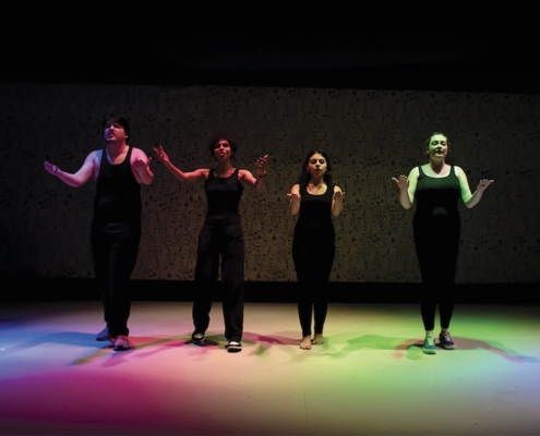 NECC theater performers performing under rainbow lights on stage