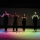 NECC theater performers performing under rainbow lights on stage