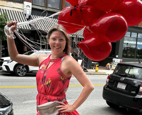 Hailey holding red balloons on the streets of Haverhill