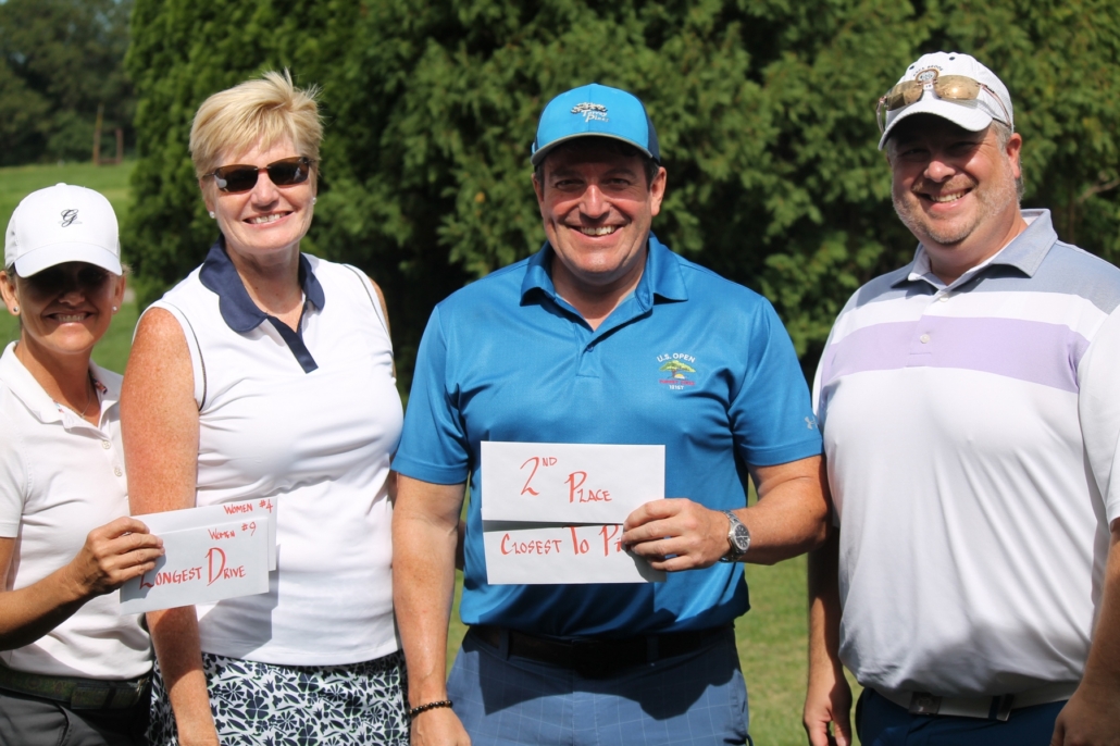 golf tournament winners hold up award