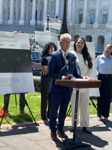 president glenn stands in front of US capitol building at a podium