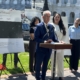 president glenn stands in front of US capitol building at a podium