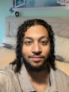 Izaiah Igartua Rivera selfie, he has chin length curly hair, a mustache, and beard