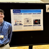 John Ryan stands next to his research poster