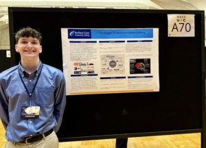 John Ryan stands next to his research poster