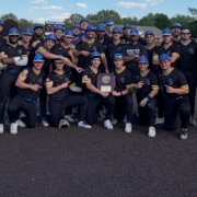 KNights team stands in black uniforms with black hats holding tournament trophy