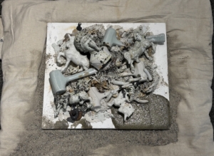exhibit of found ceramic objects affixed to a burlap backing