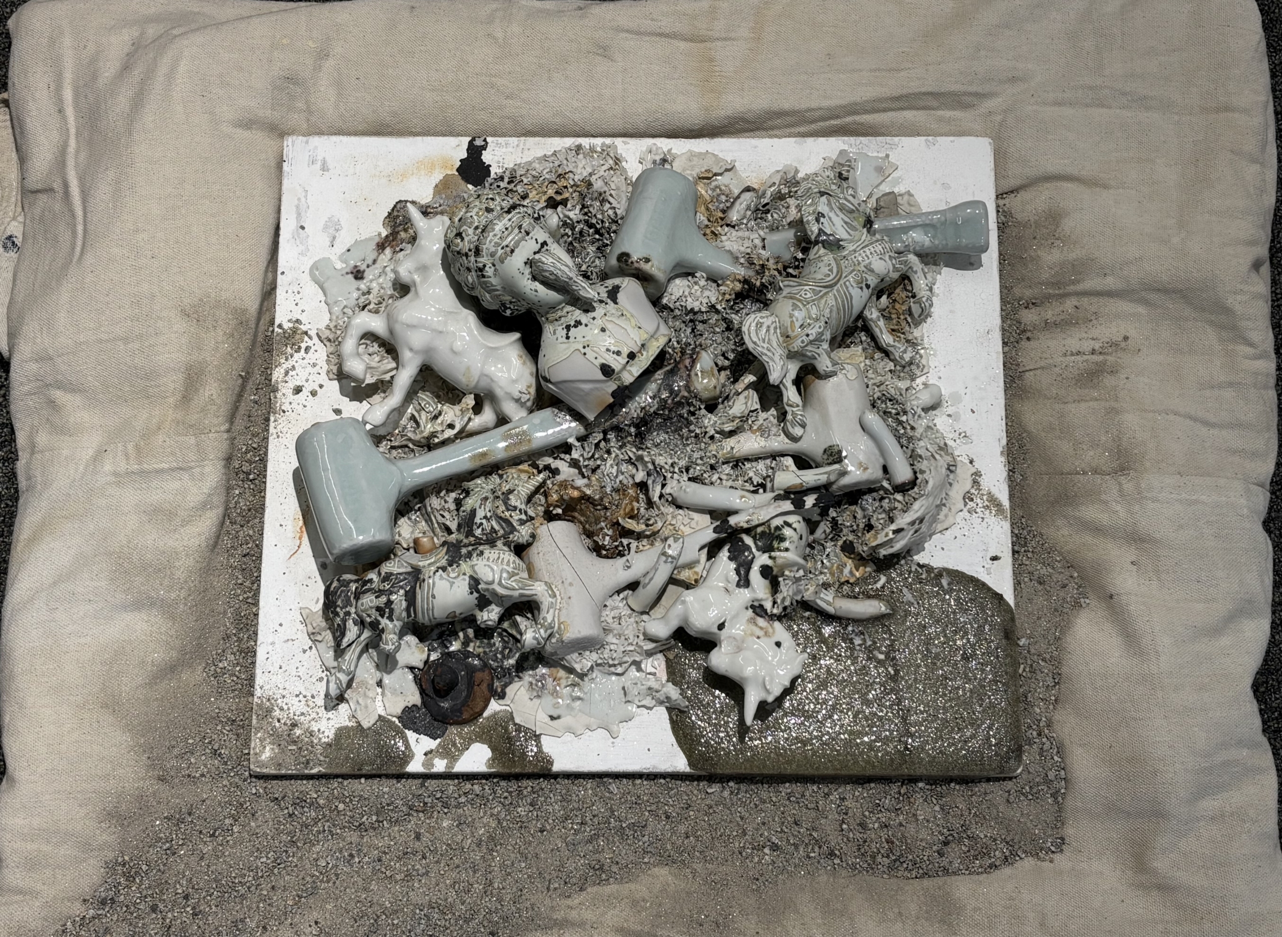 exhibit of found ceramic objects affixed to a burlap backing