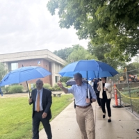 president glenn and secretary zrike walk with umbrellas on the haverhill campus