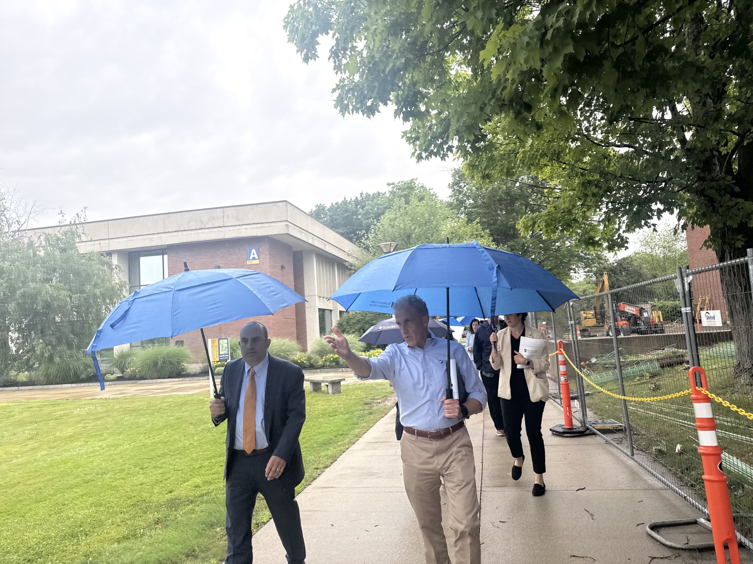 president glenn and secretary zrike walk with umbrellas on the haverhill campus
