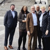 A group of adults posing and smiling for the camera in front of te steps of the capitol builing