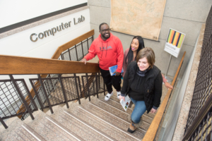 three students walk up the center staircase in the NECC library