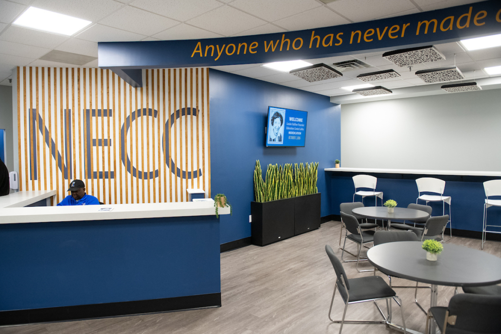 new lobby space with tables and a large sign that says NECC