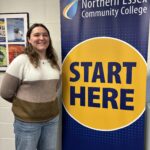 Emma posing in front of banner that says "start here"