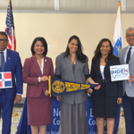 Four members of INDEX stand withe Naydeen holding NECC Pennant and Dominican flags