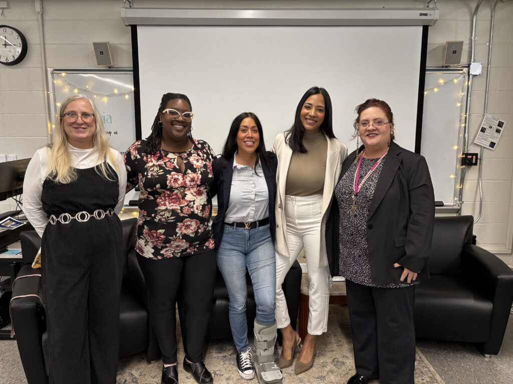 five women pose in front of classroom