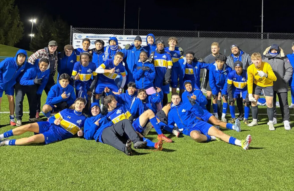 Members of the men's soccer team, in blue uniforms, pose for the camera.