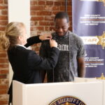 woman gives pin to young man standing behind a podium