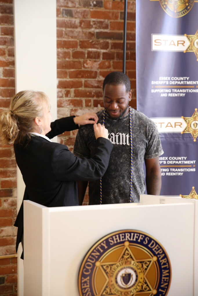 woman gives pin to young man standing behind a podium