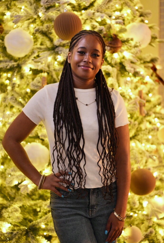 NECC Student Kenberly Prospere posing in front of a holiday scene