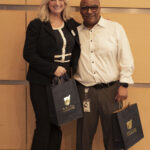 A woman and man pose with their gift bags