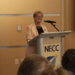 VP of HR stands behind a podium addressing group