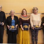 one man and four women pose with wrapped gifts