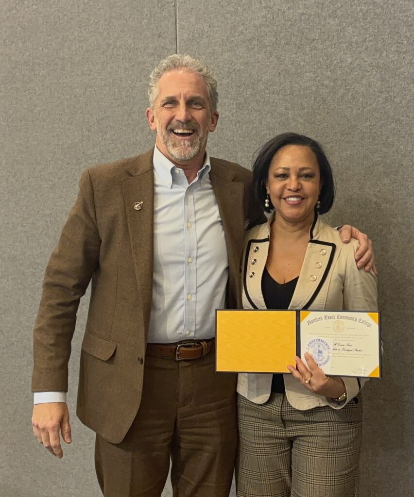 president glenn stands with his arm around zoila who is holding up her diploma 