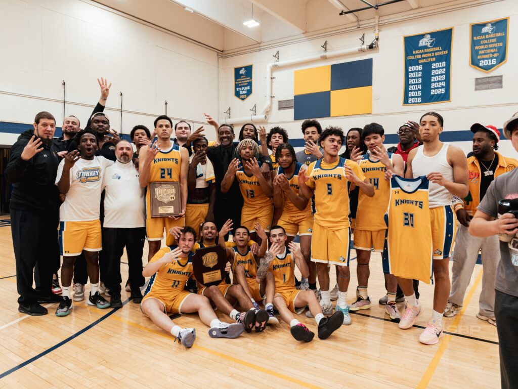 men's basketball team stands smiling at the camera