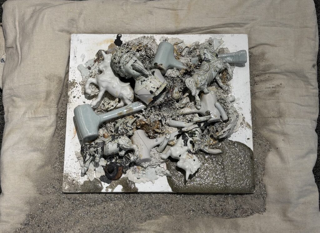 exhibit of found ceramic objects affixed to a burlap backing