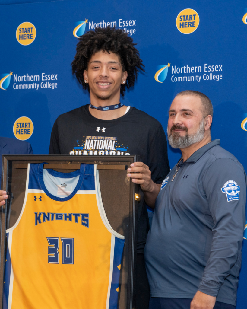 delgado stands next to darren stratton, holding framed yellow jersey with his name and number 30 on it