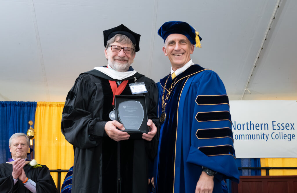 stephen russell and lane glenn pose with award. both are wearing commencement regalia