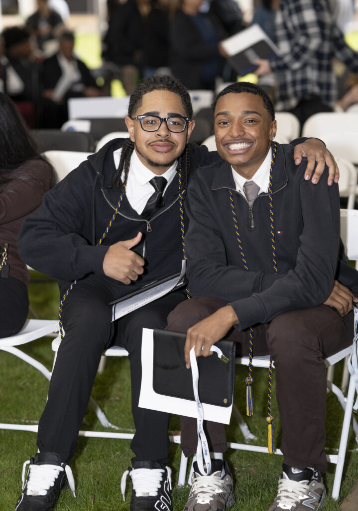 two young men, dressed in shirts and ties with a quarter zip smile at the camera