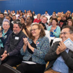 wide shot of audience smiling and clapping