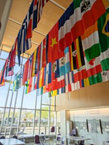 El Hefni in Lawrence main room with international flags adourning the ceiling and a large window in the background