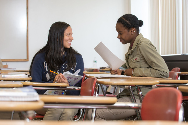 Two students talking to each other in a classroom setting
