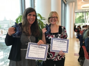 Kristen Sparrow and Clare Thompson smile holding their COD award and certificates