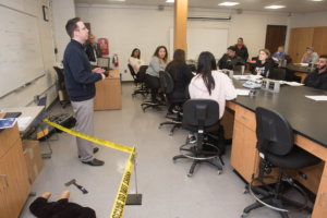 Mike Cross stands with a staged crime scene for a class